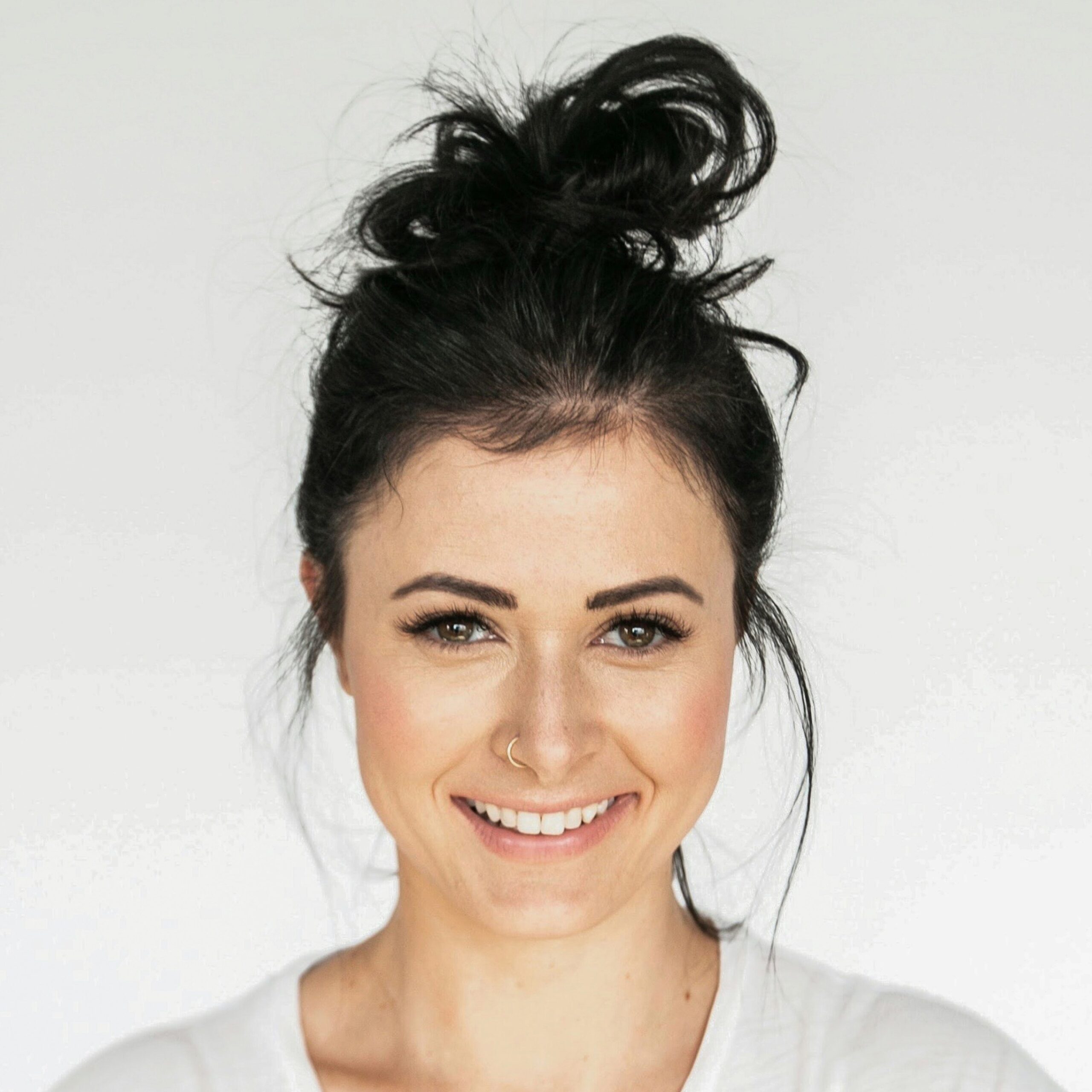 Frau mit dunklen Haaren im Dutt, lächelnd