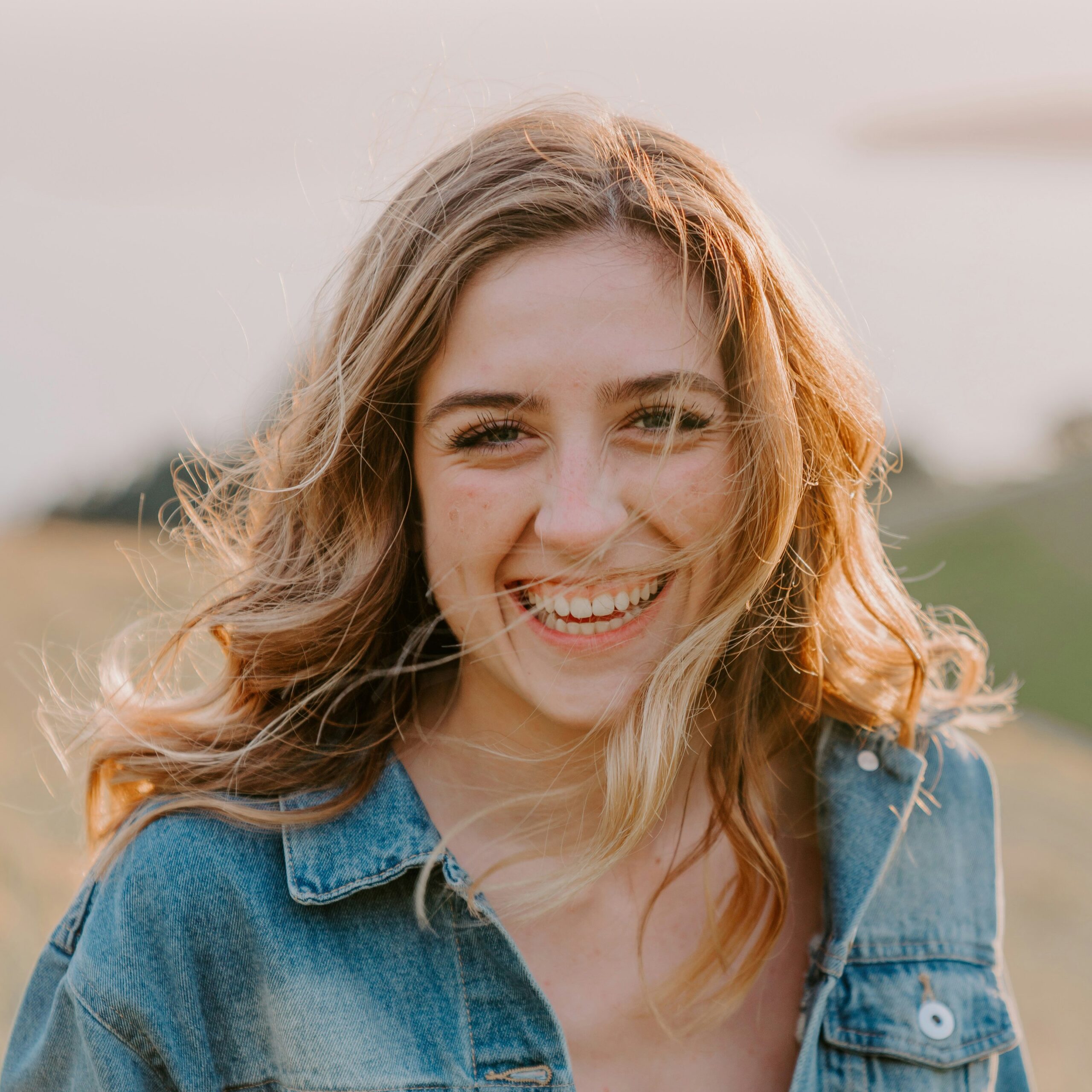 Junge Frau mit blonden Haaren, lächelnd, draußen